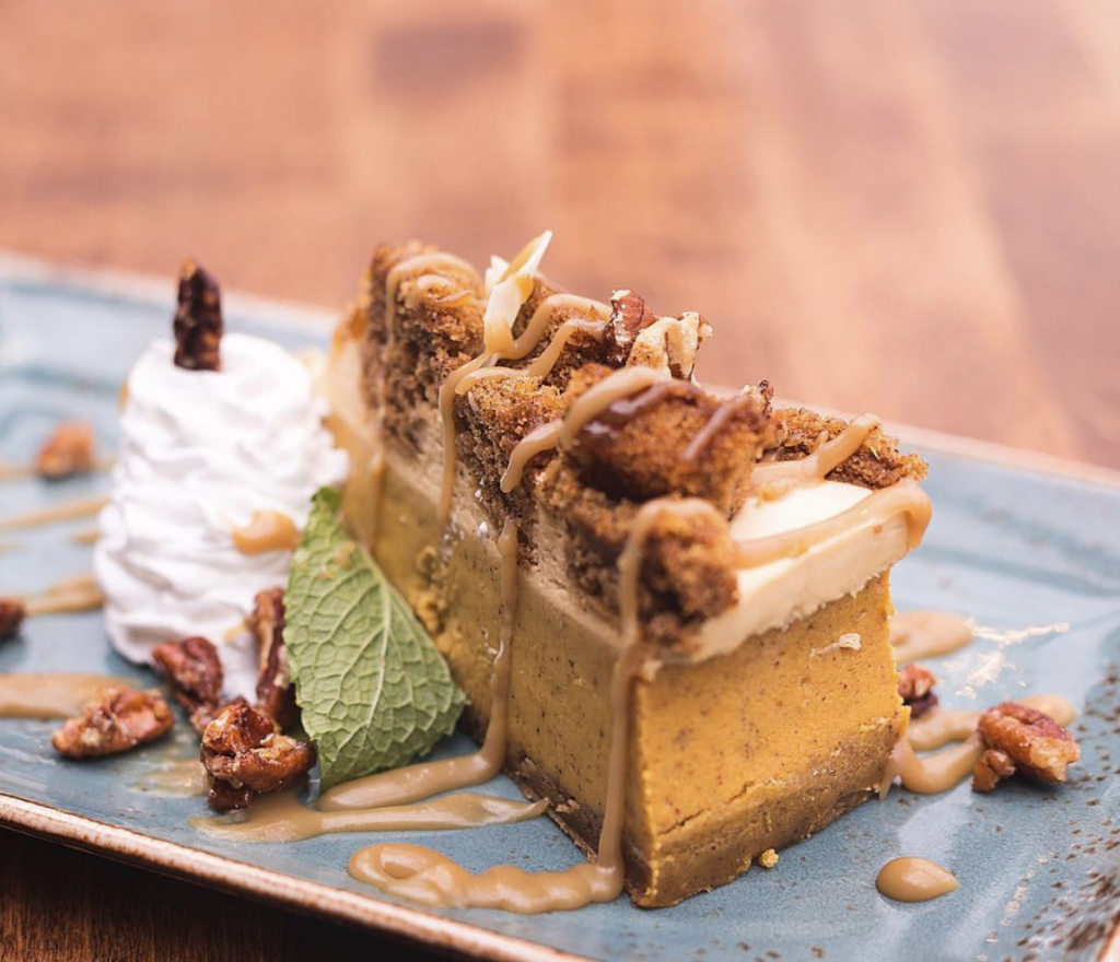 Close up of a decadent pumpkin pie topped with brown sugar crumble and pecans
